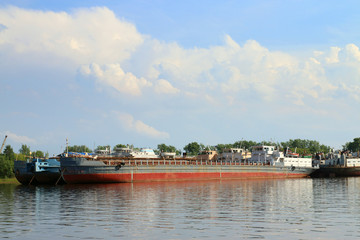 Fototapeta na wymiar Old rusty cargo ships in pure water of river at summer sunny day
