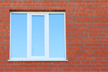 Part of red brick wall and blue window with double glazing 