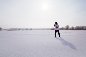winter fisherman with ice screw on frozen lake