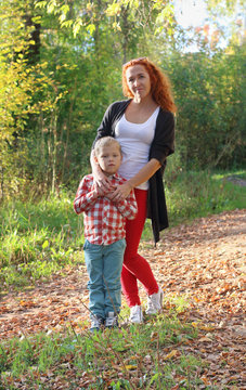 Young mother and her little son in autumn park at sunny day