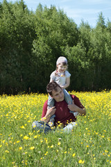 Fototapeta premium Happy father with his daughter on shoulders among yellow flowers