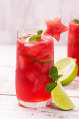 Watermelon and lime fresh in high glasses decorated by watermelon stars on white wooden table. Selective focus