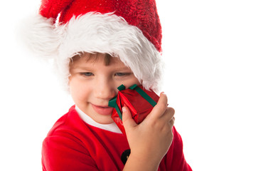 funny child in Santa red hat holding Christmas gift in hand. Chr
