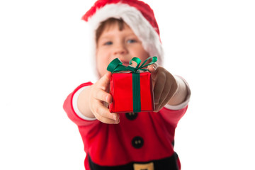 funny child in Santa red hat holding Christmas gift in hand. Chr