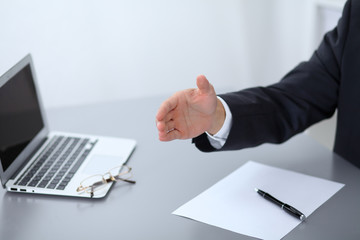 Close-up of  businessman at the table giving a hand