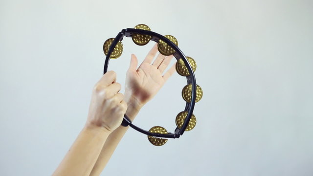 Hands playing on tambourine (shaker), shake several times on white background