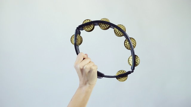 Hands playing on tambourine (shaker), shake several times on white background