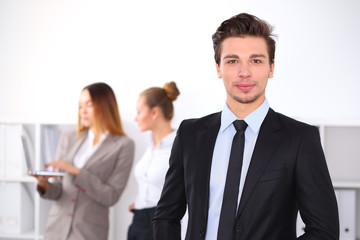 Fototapeta premium Cheerful business man in office with colleagues in the background, sturt up team