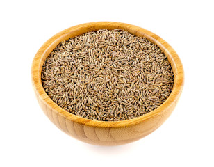 Whole cumin seed in a bowl isolated on white