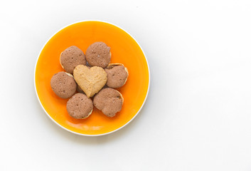 Chocolate cookies and butter cookies heart shape on orange dish on white background