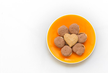 Chocolate cookies and butter cookies heart shape on orange dish on white background