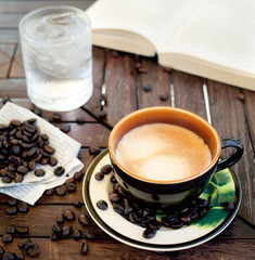 Cup of coffee, cappuccino with beans and a book.