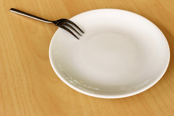 Empty plate and fork on wood table