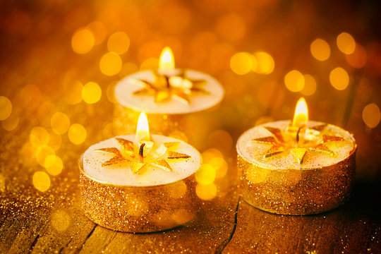 Burning candles on golden background