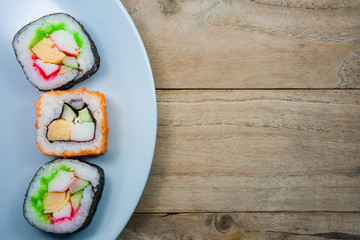 Sushi maki on a plate over wooden table