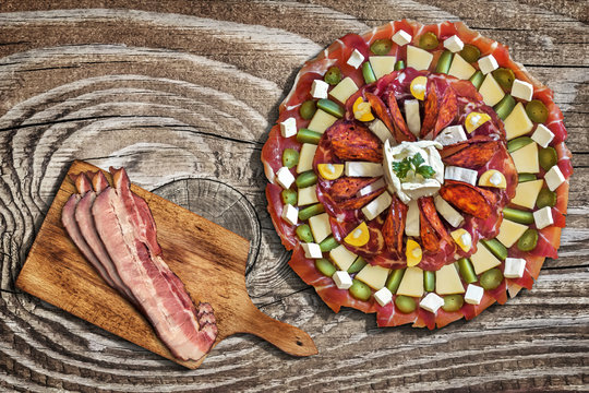 Plateful of Savory Appetizer Meze, with Bacon Rashers on Cutting Board, Placed on Old Wooden Background.