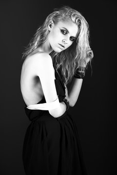 Daring girl model in black silk dress, style of rock, dark make-up, wet hair and bracelets on her arms
