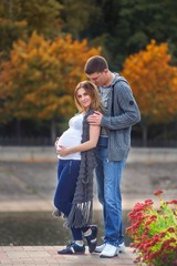 Pregnant couple - hugs with flowers near the river