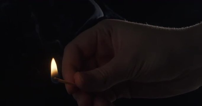 female hands firing match in dark sideview