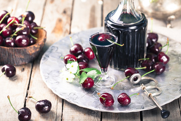 Cherry homemade liquor in a vintage bottle with fresh cherries.