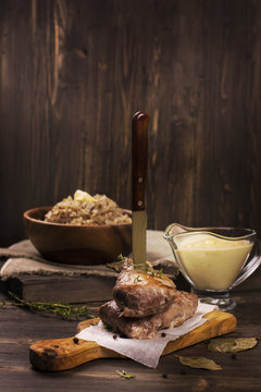 Stack of juicy pork chops, cream and corn sauce, boiled buckwheat on dark wooden table. Rustic style. Toned image. Selective focus