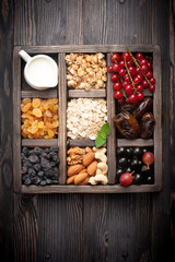 Healthy food in wooden box. Granola, berries, nuts, dried fruit and milk. Top view. horizontal