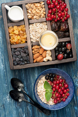 Box with products for healthy breakfast. Muesli, oatmeal, dried fruit, fresh berries  and nuts.