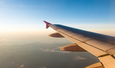 Fototapeta na wymiar Airplane Wing in Flight from window with sunset sky