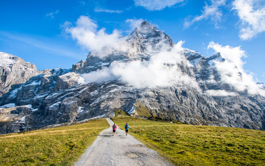 Two runners on the pass way to Grosse Scheidegg above Grindelwald, Switzerland. - obrazy, fototapety, plakaty