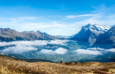 Aerial view of Grindelwad, Switzerland with surrounding mountains throw clouds.