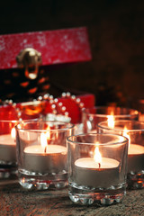 Burning candles and red box with gifts, pine cones, ribbons and