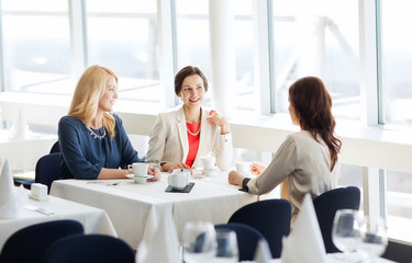 women drinking coffee and talking at restaurant