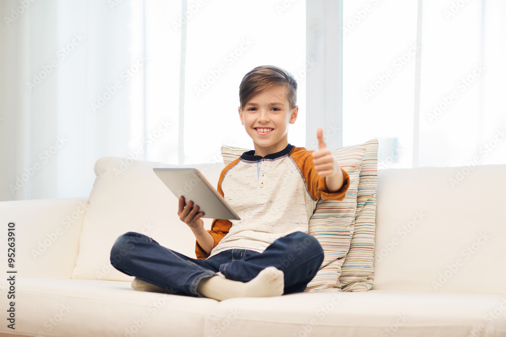 Wall mural smiling boy with tablet showing thumbs up at home