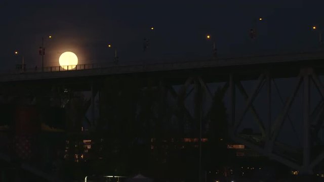 Vancouver Downtown Full Moon Set. The full moon setting at dawn over Granville Island and the Granville Street bridge on False Creek. Vancouver, British Columbia. 4K UHD. Slow motion.
