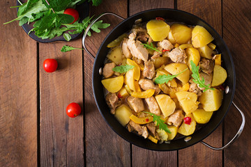 Stewed potatoes with meat and vegetables in a roasting tin on a wooden background