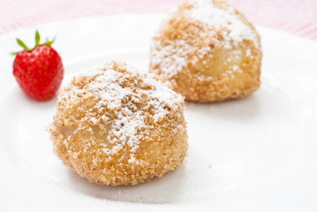 Delicious dumplings with plums on white plate. Hungarian traditional dessert