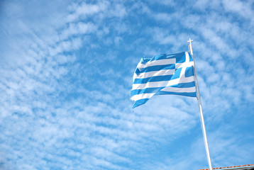 Greek flag waving against a blue cloudy sky