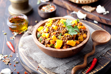 Lentil with carrot and pumpkin ragout in a wooden bowl.