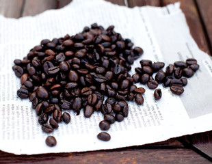 Coffee beans on a sheet of paper. Wooden background