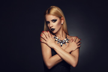 Beautiful blonde with nice makeup posing on a dark background