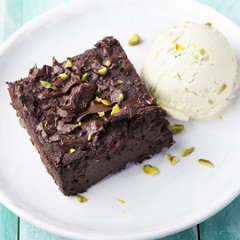 Chocolate brownie, cake, white plate on a turquoise wooden background
