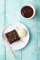 Chocolate brownie, cake, white plate on a turquoise wooden background