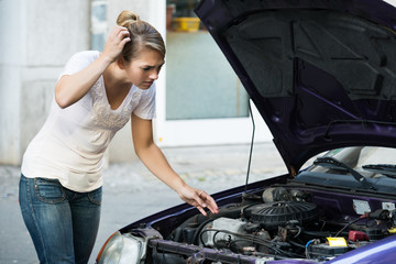 Fototapeta na wymiar Confused Woman Looking At Broken Down Car Engine