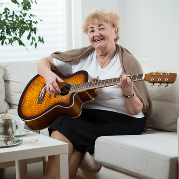 Elderly woman playing the guitar