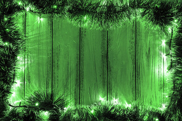 New year theme: christmas tree decoration and garland with green lights on retro stylized wood background