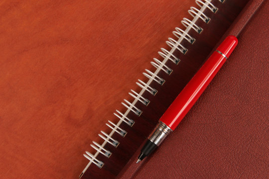 notebook and a red pen lying on wooden desk