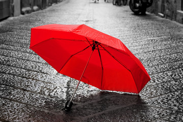 Red umbrella on cobblestone street in the old town. Wind and rain © Photocreo Bednarek