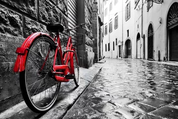 Abwaschbare Fototapete Fahrrad Retro Vintage rotes Fahrrad auf Kopfsteinpflasterstraße in der Altstadt. Farbe in schwarz-weiß
