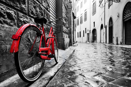 Fototapeta Czerwony rower na brukowanej uliczce na starym mieście czarno-biała XL