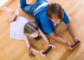 Fototapeta na wymiar Positive siblings playing with phones